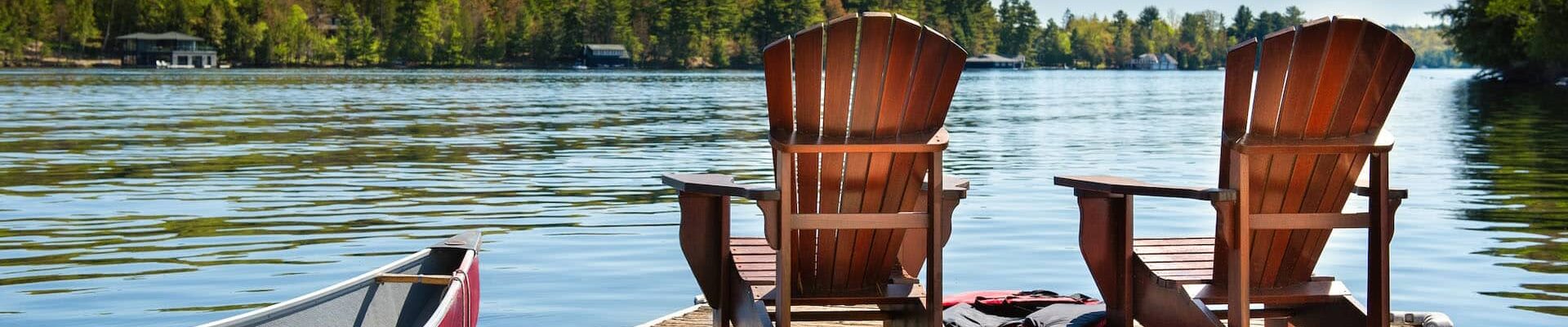 View of a pier stretching into a Texas lake with 2 chairs and a canoe